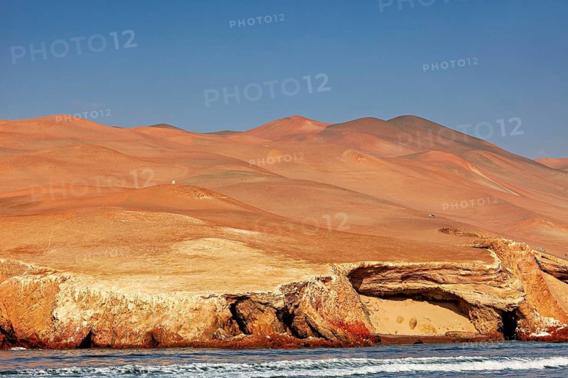 Sandy desert landscape with rocky coast under clear blue sky, The rocky coast with desert near Paracas in Peru
