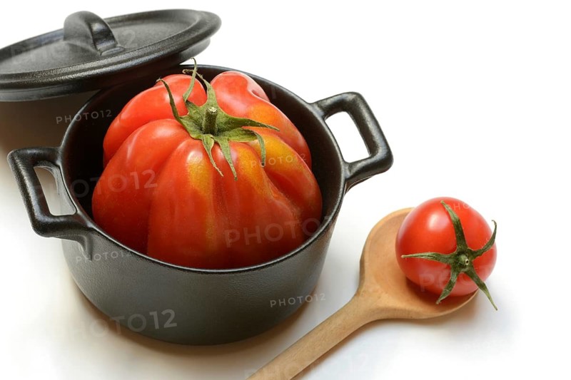 Tomato in pot and cooking spoon, oxheart tomato