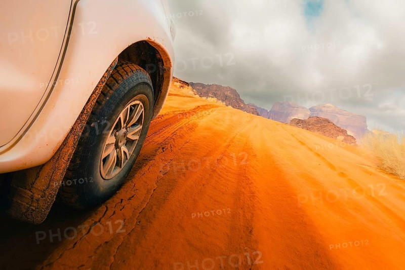 Jordan - 25th october, 2025: Close up 4wd vehicle driving across Wadi rum red sand track with desert mountains off road adventure travel. SUV driving through gravel dirt road hilly terrain landscape