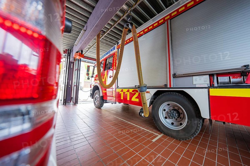 Interior view of a fire department garage with red fire engines and hoses on the ceiling, Gechingen fire department, Calw district, Germany