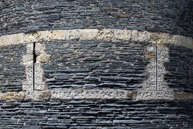 Detailed view of one of the mighty defensive towers with narrow, vertical loopholes, built of slate and limestone from Château d'Angers, Angers Castle, Angers, Maine-et-Loire department, Pays de la Loire region, France