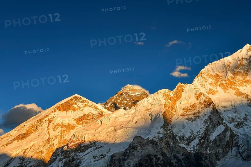 Everest base camp trek. Mountain peak. Mount Everest, Lho La, Nuptse, Lhotse peaks. Sagarmatha National Park, Nepal. Golden sunset with clear blue sky and Mt Everest peak view