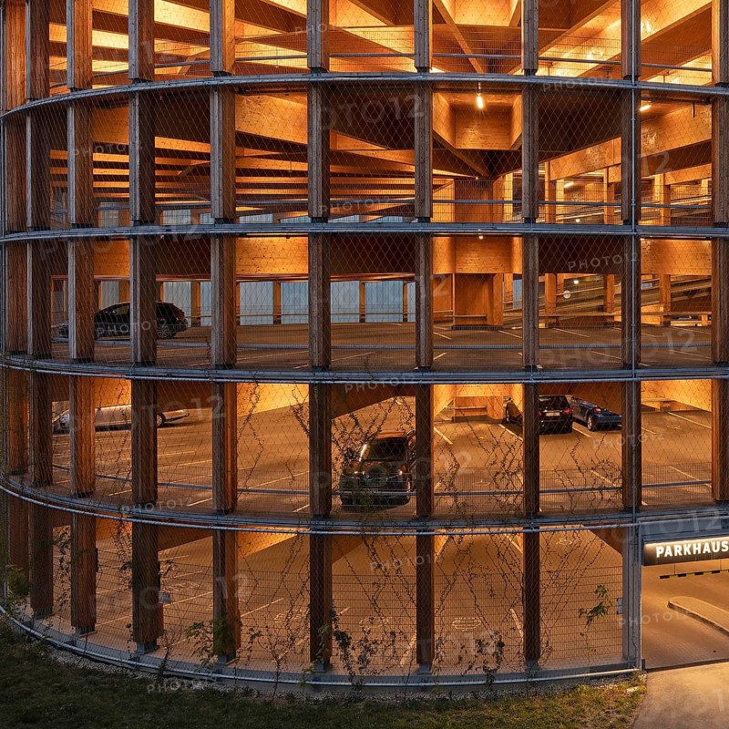 03.05.2026: Illuminated modern timber parking garage (Parkhaus am Bahnhof) with a curved wooden facade at dusk. Wendlingen am Neckar, Baden-Württemberg, Germany