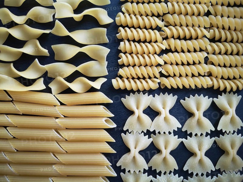 The texture of four types of pasta: tagliatelle, farfalle, penne and fusilli.Close-up. Top view. Horizontal