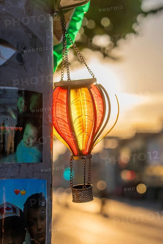 A lantern illuminated by the evening sun, next to photo stickers, Dublin, Ireland