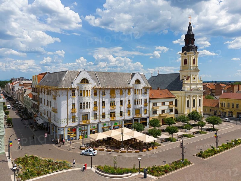 Baroque church and historic buildings on a street corner under cloudy sky, lined with trees, aerial view, palace of Adolf Moskovits and sons on the left, moon church, Piata Unirii, Unity Square, Oradea, Oradea, Bihor district, Kreischland, Transylvania, Romania