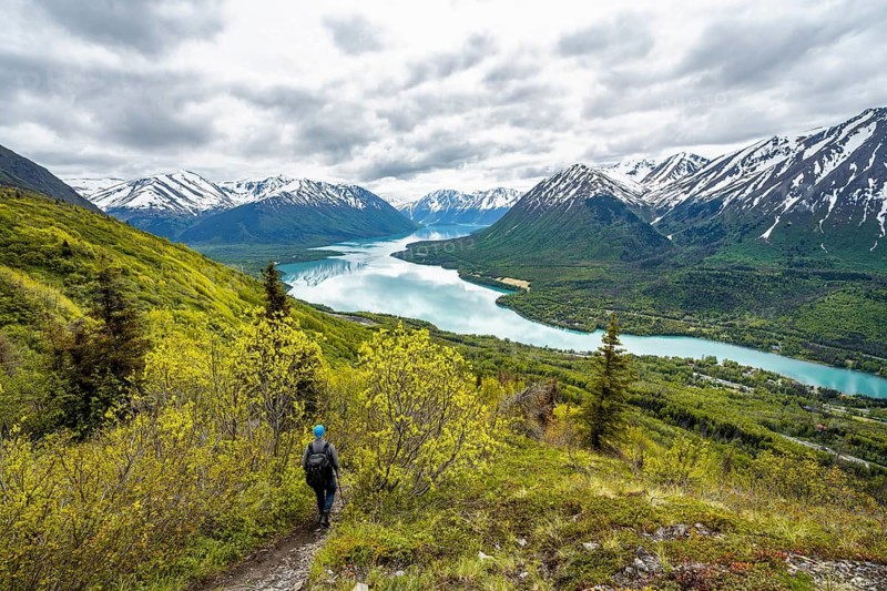 Climbers on a hiking trail, Slaughter Ridge Trail, view of snowy mountains in spring and turquoise blue Kenai Lake Lake, Cooper Landing, Kenai Peninsula, Alaska, USA