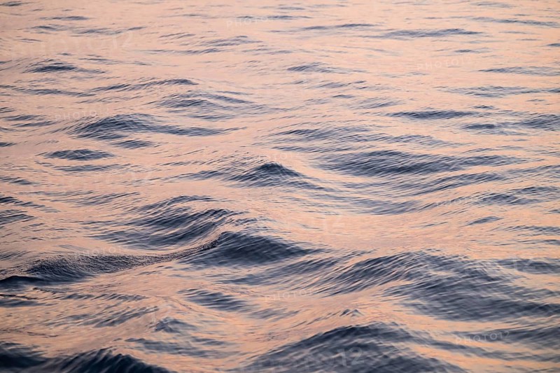 Gentle waves of the Mediterranean reflect a pink-blue light with a calm atmosphere, Aeolian or Lipari Islands, Southern Italy, Italy