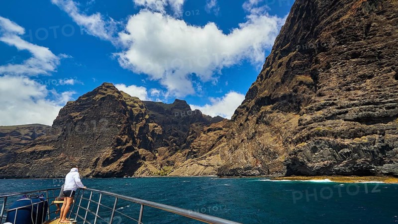 Los Gigantes, person on a boat admiring the impressive rock formations under a partly cloudy sky, whale watching boat tour, whale watching, whale, dolphins, west coast, Tenerife, Canary Islands, Spain
