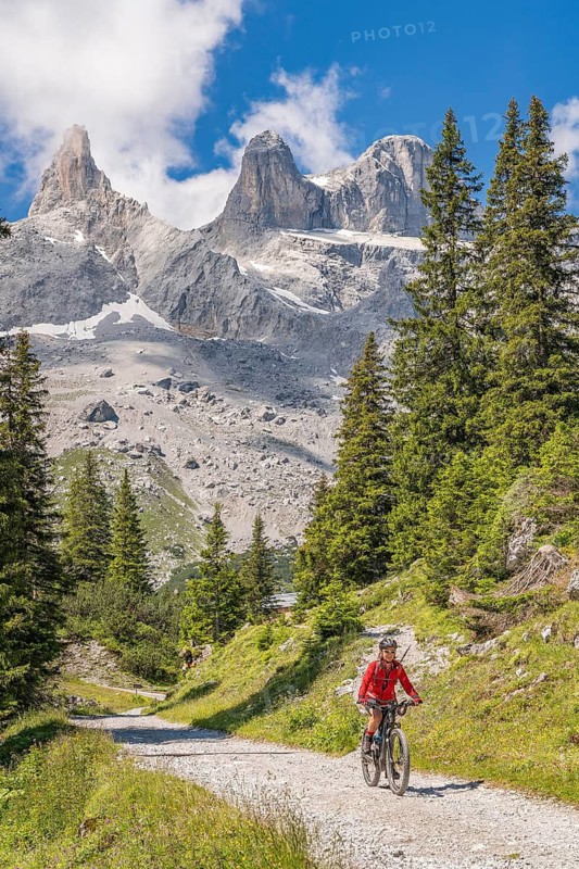 Woman riding her electric mountain bike up to the Lindau Hut below the famous summits of Drusenfluh and Three towers in Schruns, Montafon, Vorarlberg Austria