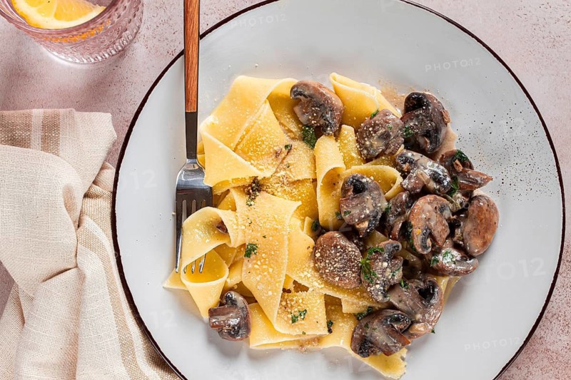 Delicious pappardelle pasta with mushrooms and cream served on a white plate