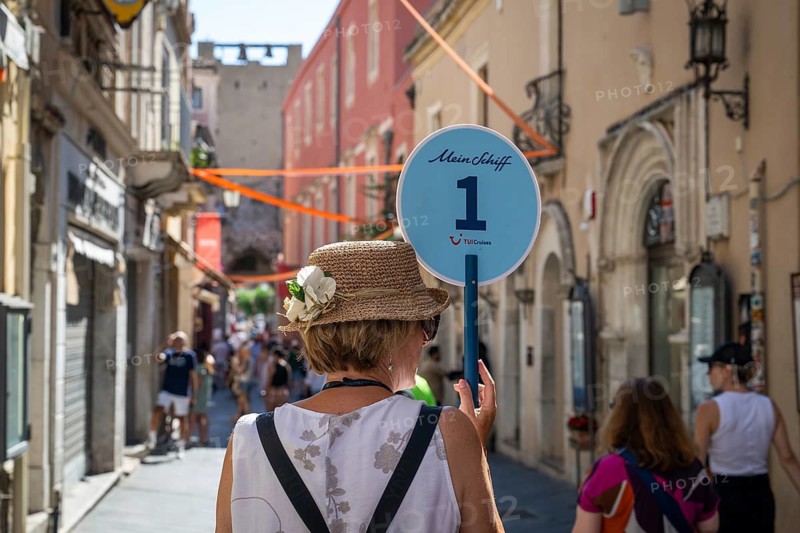 Woman holding sign with the inscription Mein Schiff 1 in die Höhe, Taormina, Sicily, Italy