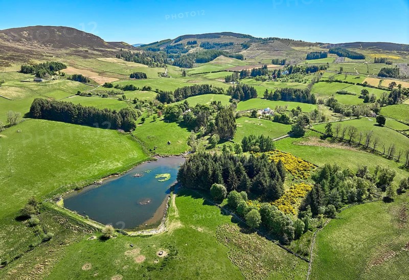 Aerial drone photo of agricultural landscape with meadows and pastures at the border of the Cairn Gorm National Park, Scotland, UK