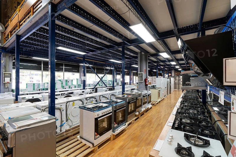 Modern retail store interior displaying a wide selection of new home appliances including washing machines, ovens, stoves, and refrigerators, ready for purchase and delivery