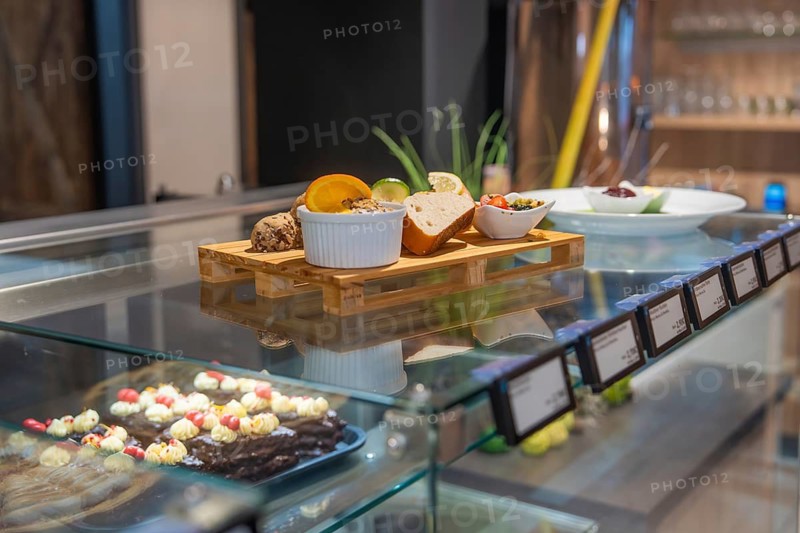 Colourful selection of baked goods and sweets presented in a glass display case on wooden table, breakfast at Cafe Kuh, Deckenpfronn, Germany