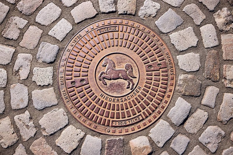 Manhole cover, coat of arms of Lower Saxony, horse, cobblestones, sunny, Bramsche, Osnabrück district, Lower Saxony, Germany