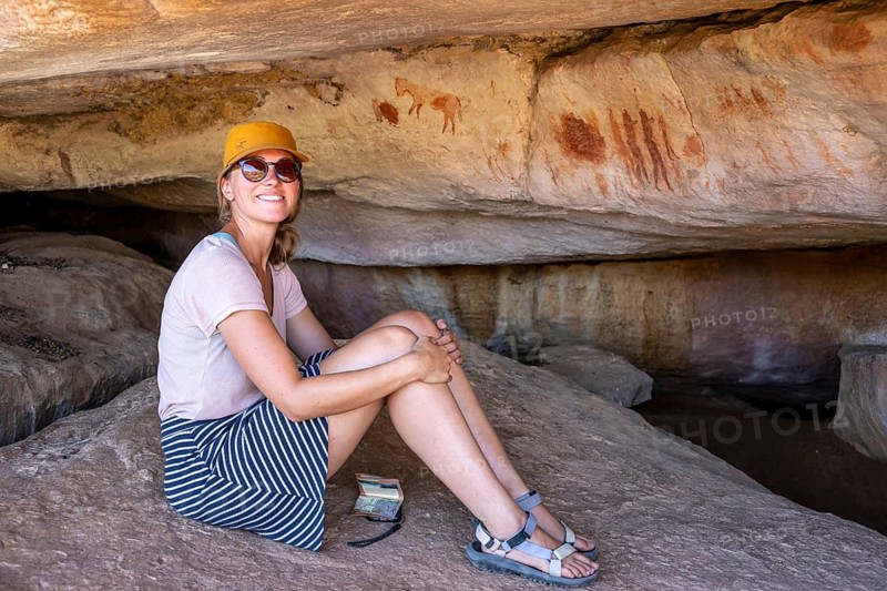 Tourist on a rock with prehistoric animal depictions, ancient rock carving of the San, indigenous people of South Africa, Seville Rock Art Trail, Cedar Mountains, Clanwilliam, Western Cape, Republic of South Africa