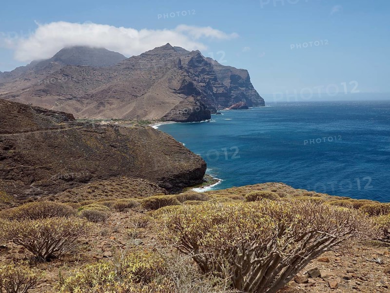 Arid landscape with sea views and rocky hills under clear sky, La Aldea de San Nicolas, Gran Canaria, Spain