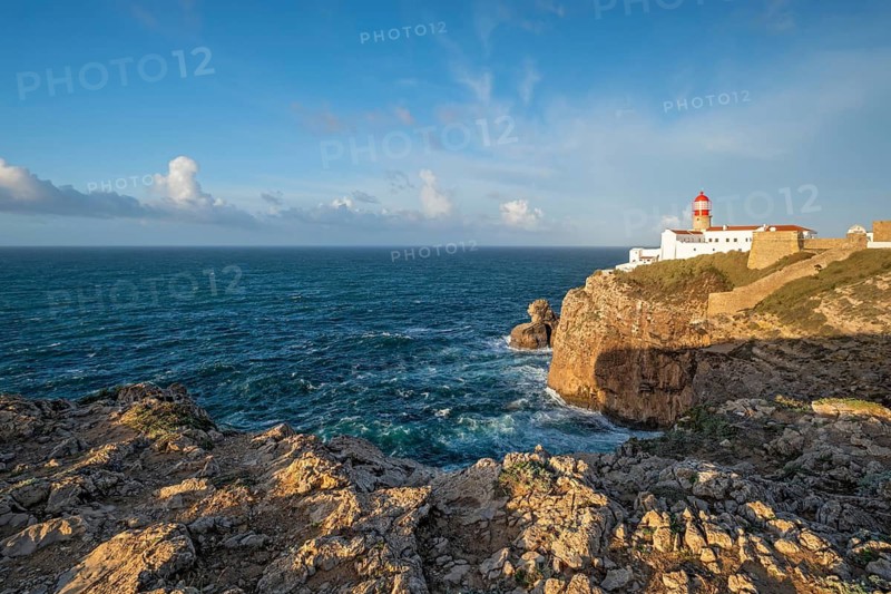 View of the Lighthouse of Cabo de Sao Vicente in Sagres, Algarve, Portugal, at sunrise with Atlantic ocean, cliffs, and clear ocean horizon