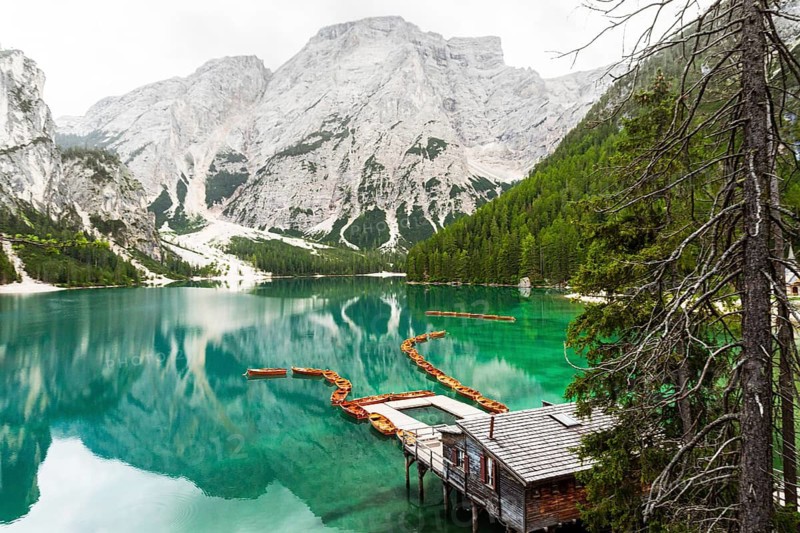 Summer vibrant landscape viewpoint s Lago di Braies Lake in italian Dolomites mountains in northern Italy. Drone aerial photo with Wooden boats and beautiful reflection in calm water at sunset