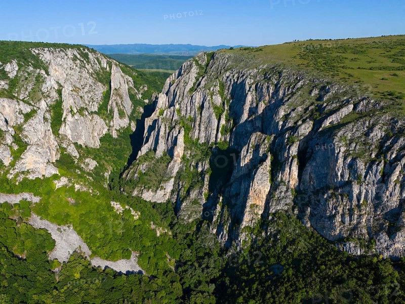 Natural rough rocks surrounded by a green landscape bordering a blue sky, aerial view, Cheile Turzii, Turda Gorge, Thorenburg Gorge, Turda, limestone gorge in the Trascau Mountains, Trascau, nature reserve, Western Carpathians, Transylvania, Romania