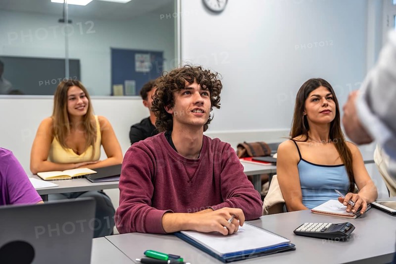 Happy university students in a modern classroom actively listening and engaging with the lecturer, focusing on education, learning, and knowledge acquisition