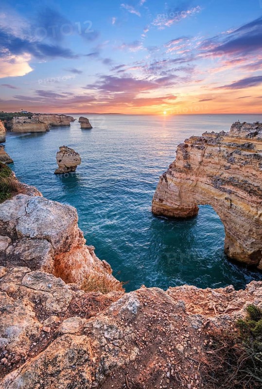 Sunrise at Praia da Marinha beach in Algarve, Portugal, with ocean cliffs, sea stacks and glowing coastal scenery