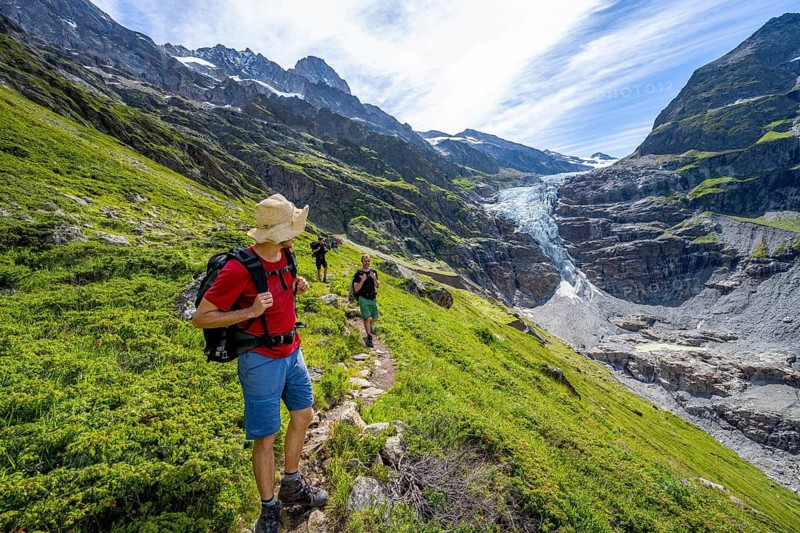 Mountaineers on a hiking trail in front of picturesque high alpine mountain landscape with Lower Arctic Sea glacier, hiking to Schreckhornhütte, Bernese Oberland, Switzerland