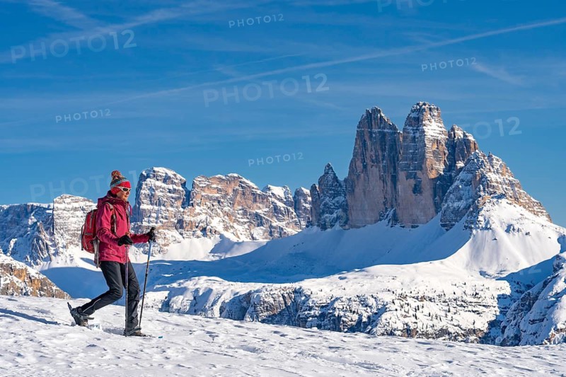 Active senior woman hiking in winter with snow shoes under the famous Three Peaks, Dolomites, Toblach, South Tyrol, Italy