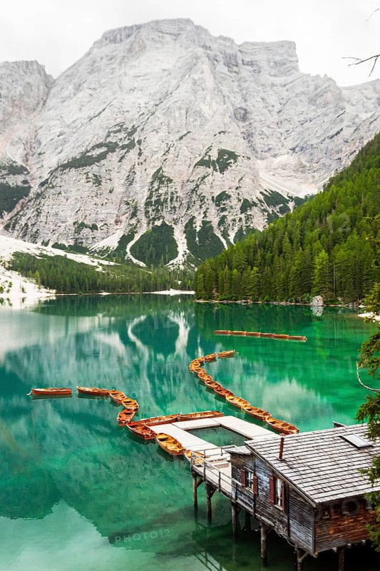 Summer vibrant landscape viewpoint s Lago di Braies Lake in italian Dolomites mountains in northern Italy. Drone aerial photo with Wooden boats and beautiful reflection in calm water at sunset