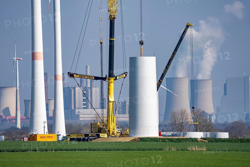 Construction site of the new Bedburg 3 wind farm, on recultivated open-cast mining site, 9 wind power plants with an output of 60 megawatts are newly built, installation of the wind turbine tower, in the background the Neurath lignite power plant, operated by RWE and the city of Bedburg, North Rhine-Westphalia, Germany