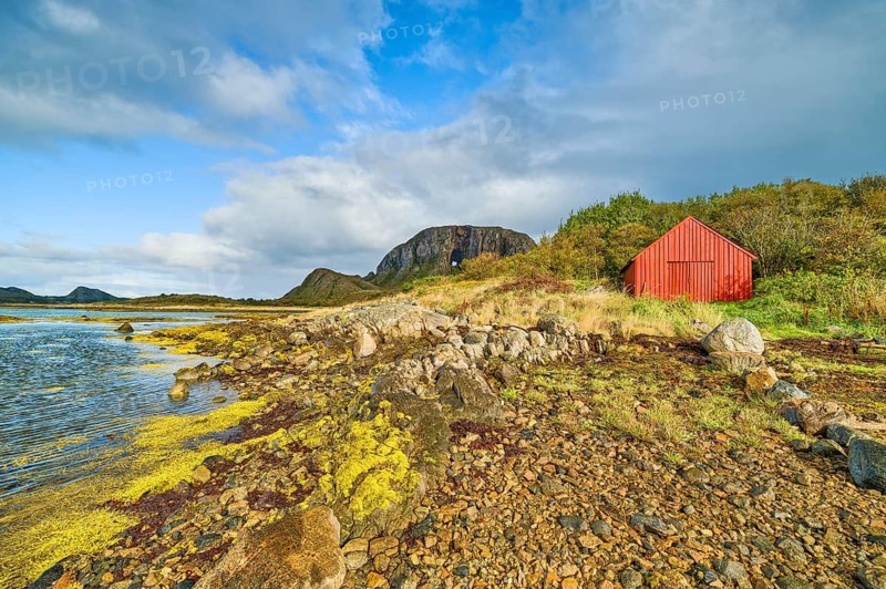 A red house on a rocky coast under a cloudy sky, sea, Torghatten, mountain, Brønnøysund, Helgelandskysten, Norway