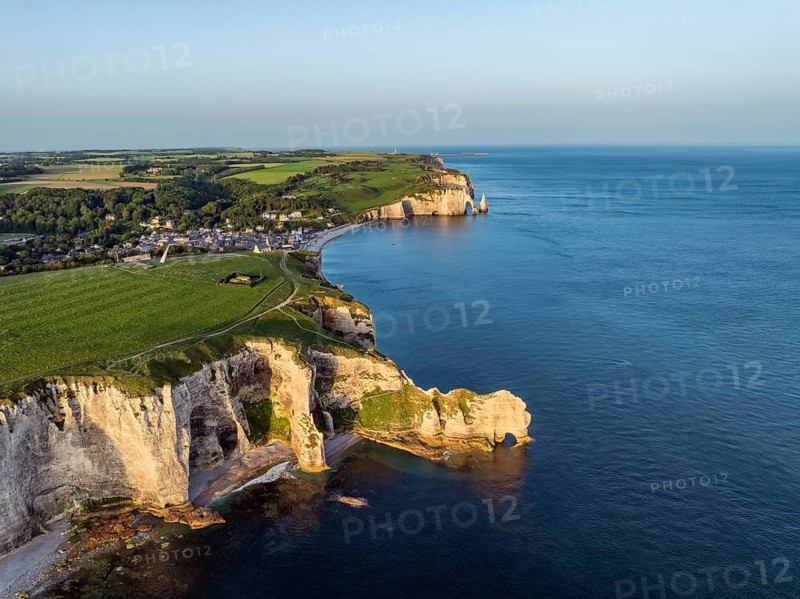 Aerial view of the Porte d'Amont rock formation, Falaise d'Amont shortly after sunrise, a landmark and natural beauty on the chalk coast with the distinctive rock gate, behind it the holiday resort of Étretat with the beach, on the right the Porte d'Aval rock formations, Alabaster Coast, La Côte d'Albâtre, chalk cliffs, English Channel, Seine-Maritime, Normandy, France