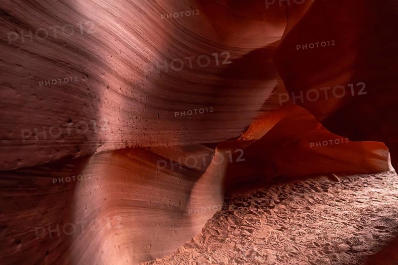 Antelope canyon slot canyon in page, arizona, showcasing swirling red orange sandstone walls, smooth flowing textures, sandy floor with faint footsteps and dramatic light and shadow play