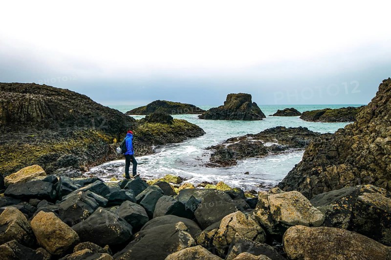 One person is stadig on rocky shore and looking to the sea. Northern Ireland