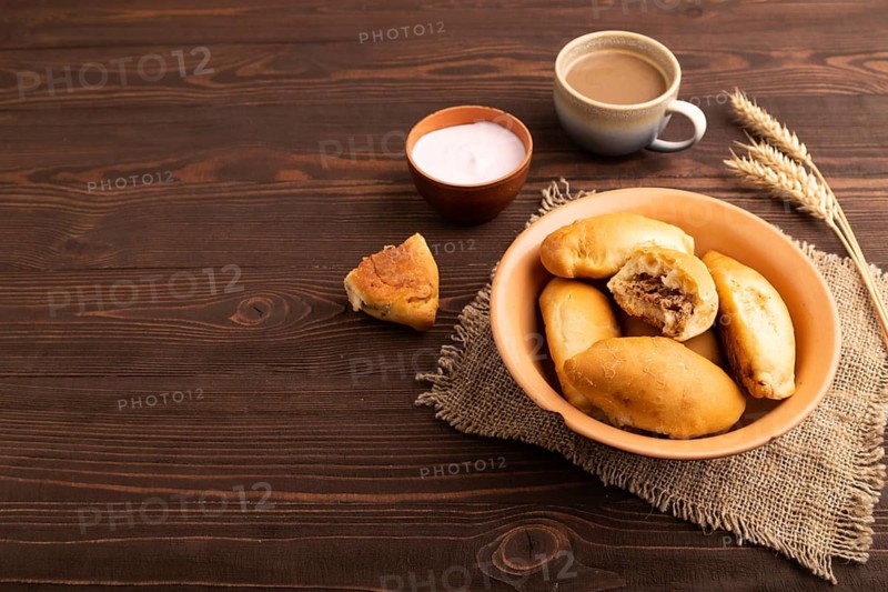 Homemade pies with jam and curd, cup of coffee, on brown wooden background with linen textile, copy space, side view