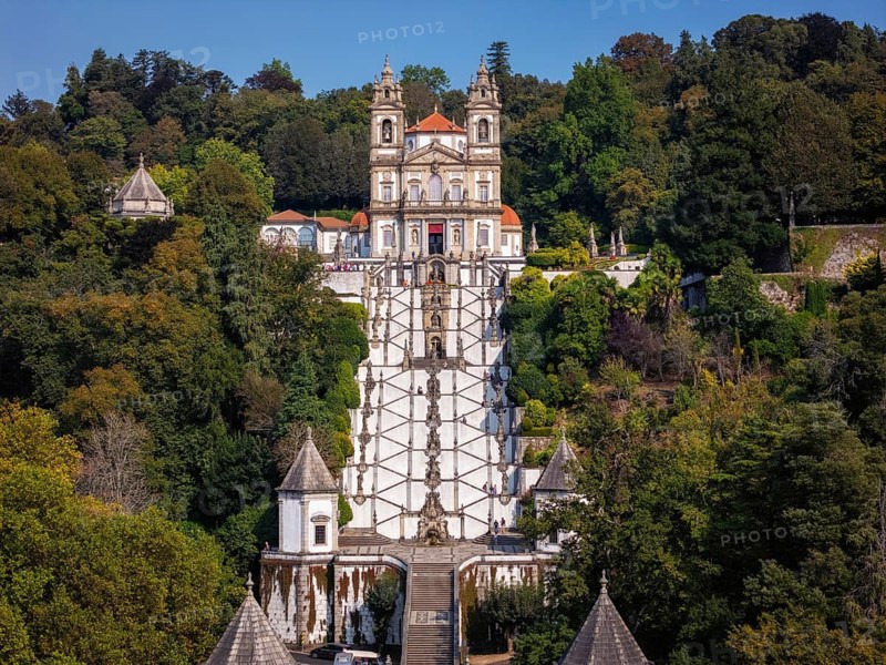 Aerial view of Bom Jesus do Monte in Braga, Portugal. The image shows the sanctuary, church, and the long staircase surrounded by trees. This landmark is a major site for visitors