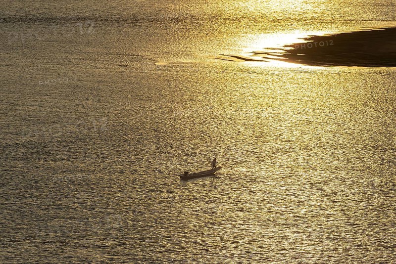Fisherman with longtail boat (Thai: Ruea Hang Yao) at sunrise, Mekong between Thailand and Laos