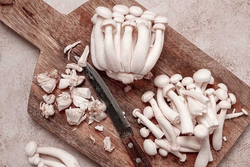 Freshly sliced Shimizhi mushrooms, on a wooden chopping board, ready to cook, close-up, no people
