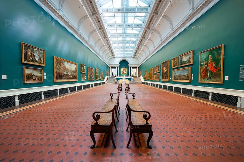 A long gallery space with paintings on green walls and benches under a skylight, National Gallery of Ireland, Dublin, Ireland