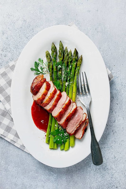 Roast duck breast, with asparagus, with red sauce, on a white plate, homemade, no people