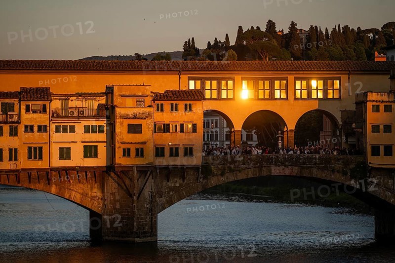 Warm evening light falls on the historic Ponte Vecchio segmental arch bridge across the Arno River and is reflected in window panes, evening mood, old town, Florence, Tuscany, Italy
