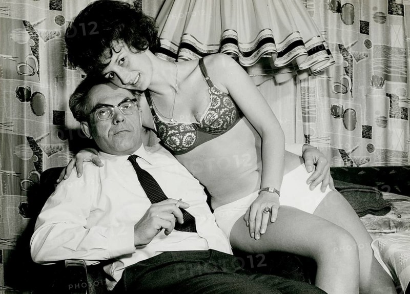 A man is sitting whilst a woman leans on his lap in a provocative pose, 1960s, Herbert Jacobi (1915–1978), Self-Portrait, 1966