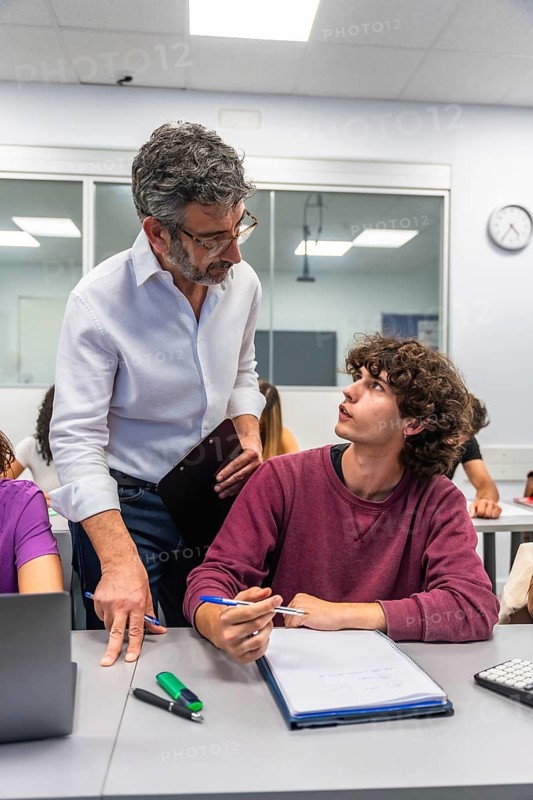 Teacher and student collaborating in a brightly lit educational setting, with the teacher providing guidance and the student actively listening, facilitating an effective learning process