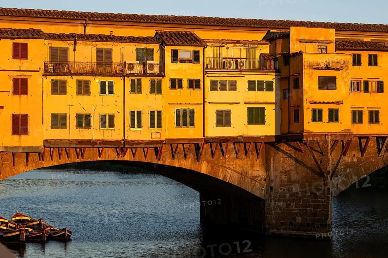 Wooden boats, Arno river, warm evening light on the historic Ponte Vecchio segmental arch bridge, evening mood, old town, Florence, Tuscany, Italy