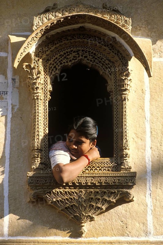 Young woman looking out of a decorated window, Jaisalmer, Rajastan, India