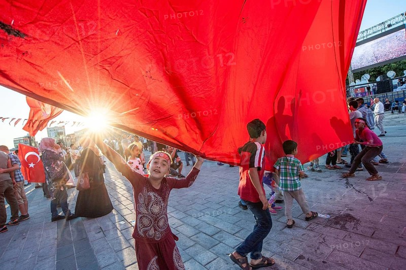 Istanbul, Turkey. 19th July 2016. Children play with a giant Turkish flag among the crowds that fill Taksim Square in Istanbul to celebrate the failure of attempted coup d'état against the Akp ruling government of Recep Tayyip Erdogan, Turkey