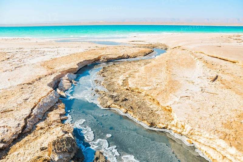 Landscape view turquoise Dead Sea water with white salt foam and ripples