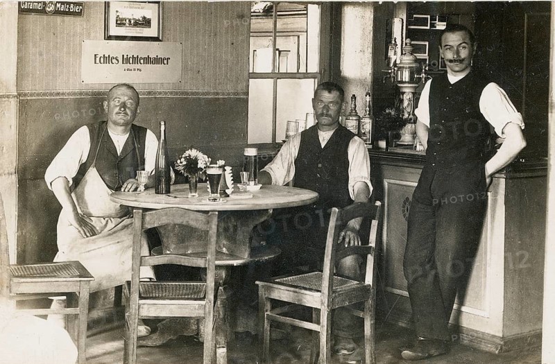 Hall, pub, restaurant, guests, Lichtensteiner beer, sales, Three men in traditional clothes sitting at a bar table with drinks, around 1925