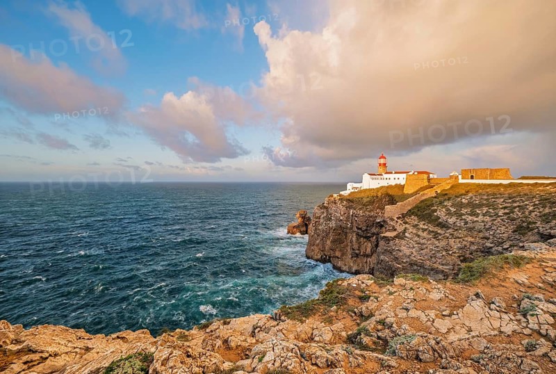 View of the Lighthouse of Cabo de Sao Vicente in Sagres, Algarve, Portugal, at sunrise with Atlantic ocean, cliffs, and open sea and cliffs